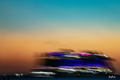 Bateaux de Nuit — navire aux lumières bleues et violettes étirées devant un ciel turquoise et orangé, photographie Bybadr.